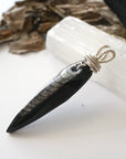 Left angle close-up of Orthoceras fossil pendant for men – unique wire-wrapped artistry, black fossil, 925 sterling silver, prehistoric jewelry.