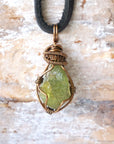 Handcrafted raw peridot necklace for men, front view – artisan bronze copper wire wrapping, August birthstone, black leather cord.
