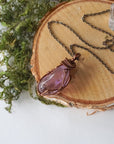 Detailed front view of women’s amethyst pendant, lighter violet stone, artisan wire wrapped in antique bronze copper