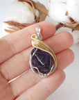 Amethyst necklace in hand for size reference, polished dark amethyst pendant, silver and gold plated copper artisan wire wrap