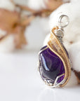 Left side angle of women’s amethyst necklace, polished dark amethyst pendant, silver and gold plated copper wire wrap