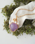 Amethyst and freshwater pearl pendant on gold plated brass chain laying flat, handmade wire wrapped jewelry for women