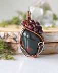 Detailed front view of a bloodstone pendant necklace with garnet accent beads and wire wrapped design