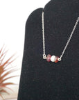 Focused left-side close-up of sterling silver garnet and pearl bar necklace on jewelry display