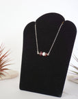 Left angle view of garnet and pearl bar necklace in 925 sterling silver on jewelry display