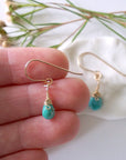 Gold turquoise dangle earrings held in hand showing size and length of handmade wire wrapped crystal drop earrings
