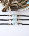 Three men's aquamarine bracelets side by side, showing natural variation in aquamarine color, antique bronze wire, black leather, Designs by Nature Gems
