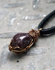 Left side angle view of a men’s garnet wire wrapped necklace, showing the antique bronze copper wrap and natural garnet stone