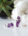 Side angle view of minimalist amethyst jewelry set showing polished raw amethyst pendant and amethyst stud earrings in silver
