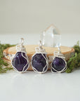 Three natural amethyst pendants showing variation in stone color, size, and shape, handmade wire wrapped jewelry