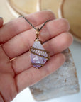 Raw amethyst point pendant necklace on antique bronze chain held in hand for size reference