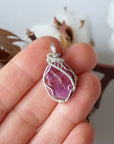 Raw pink ruby pendant in hand for size reference, sterling silver artisan wire wrapped necklace