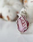 Side angle of raw ruby pendant, sterling silver artisan wire wrapping, showing detail and craftsmanship