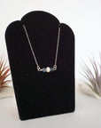 Right angle view of sapphire and freshwater pearl bar necklace in 925 sterling silver on jewelry display
