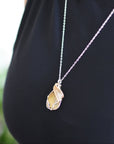 Side view of woman wearing silver gold plated citrine pendant necklace - two tone wire wrapped crystal healing jewelry