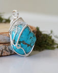 Side angle turquoise pendant showing wire wrap depth and artisan detail