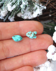 Turquoise stud earrings held in hand showing size reference - approximately 6-9mm natural stones with sterling silver posts