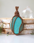 Front detail view of wire wrapped turquoise pendant showing intricate antique bronze copper wire work and polished oval stone