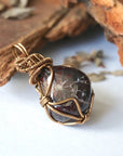 Side angle view of a women’s garnet wire wrapped necklace, highlighting the antique bronze copper wrap and gemstone profile