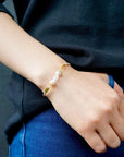 Women’s pearl and moonstone leather bracelet worn on a female model’s wrist, featuring freshwater pearls and rainbow moonstone