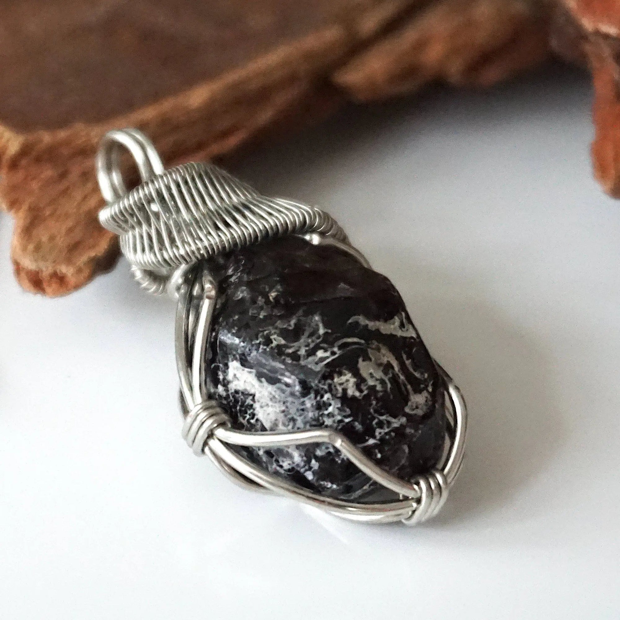 Right angle close-up of apache tears obsidian pendant – highlighting unique wire-wrapped artistry, volcanic glass, inclusive jewelry.