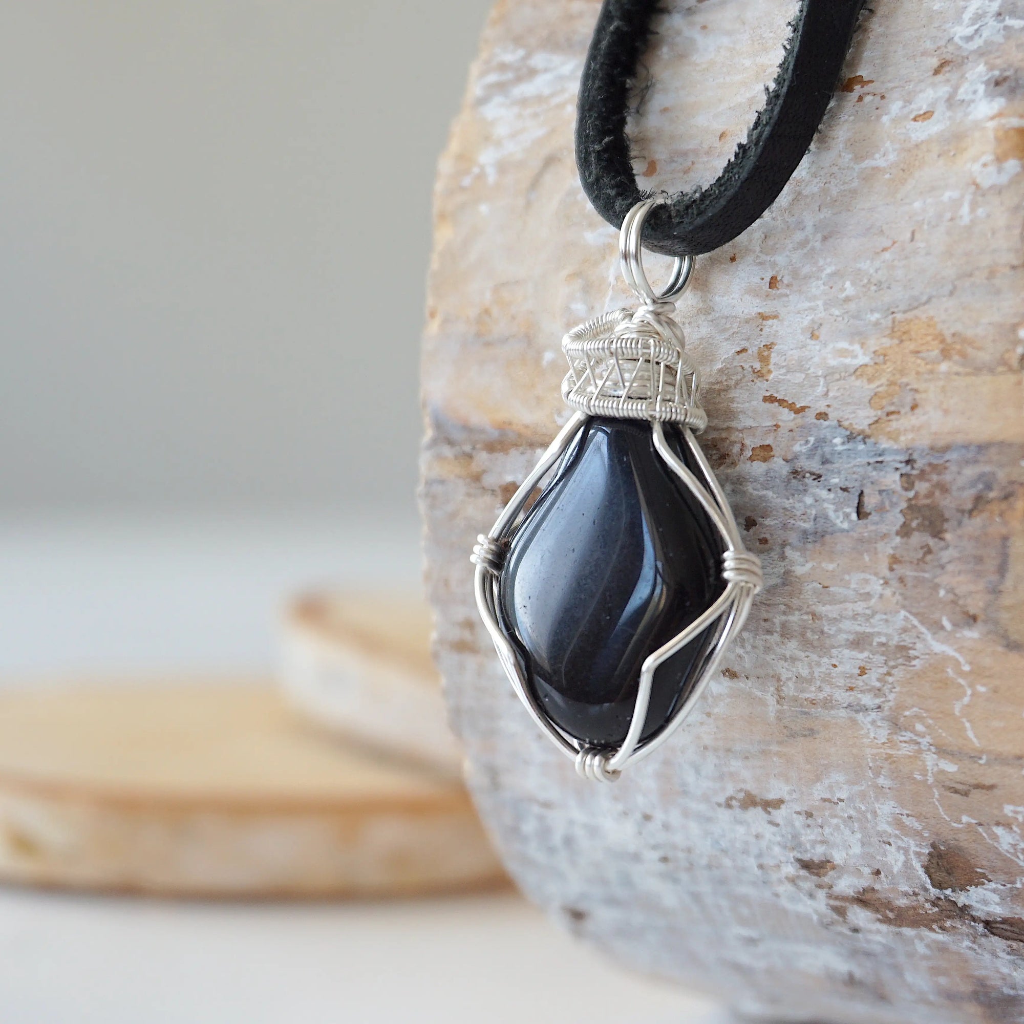 Left angle close-up of men's black onyx necklace – highlighting unique wire-wrapped artistry, black onyx, flat black leather cord.