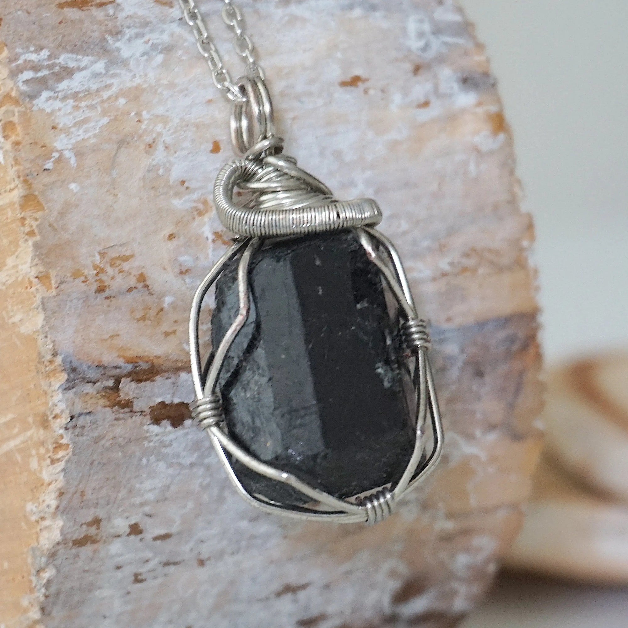 Right angle detail of raw black tourmaline necklace for men – highlights artisan dark silver copper wire wrapping and bold stone texture.