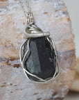 Right angle detail of raw black tourmaline necklace for men – highlights artisan dark silver copper wire wrapping and bold stone texture.