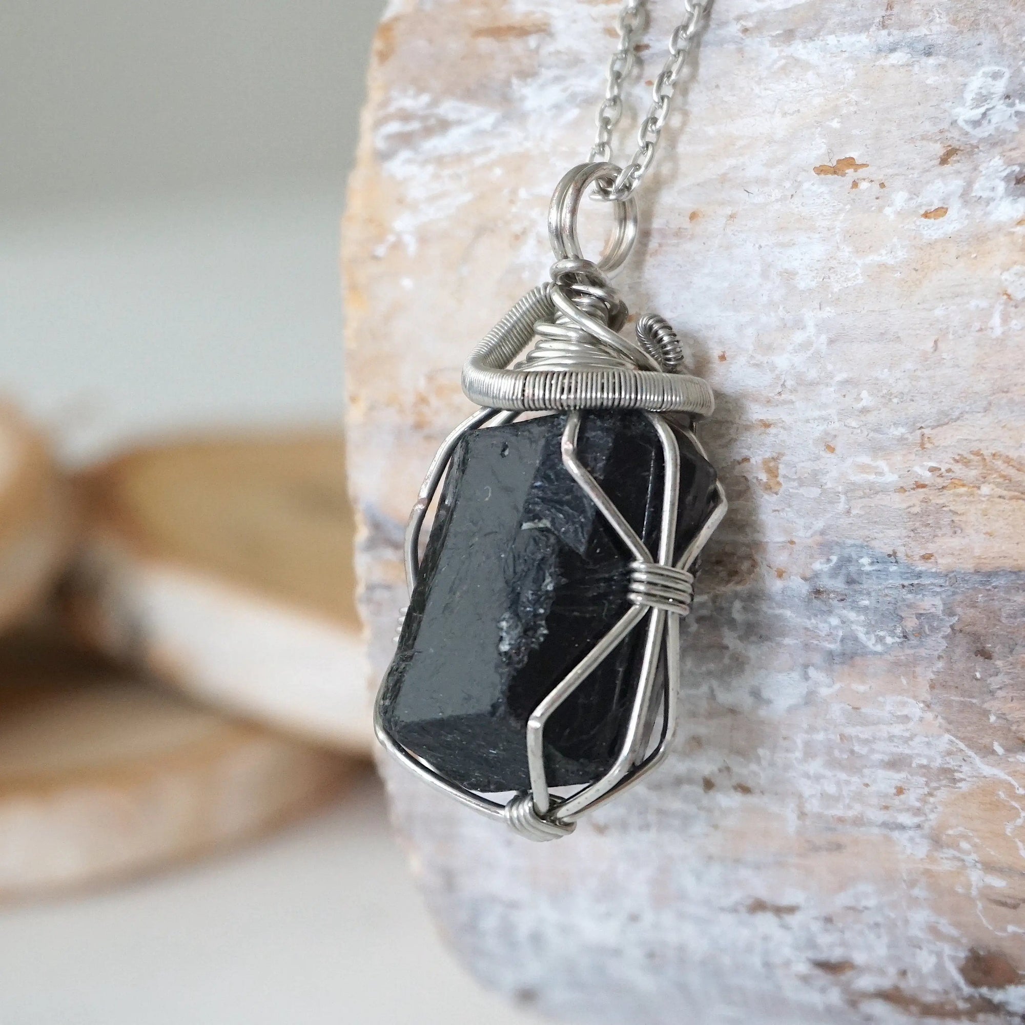 Left angle detail of raw black tourmaline necklace for men – close-up of wire wrapping and deep black tourmaline.