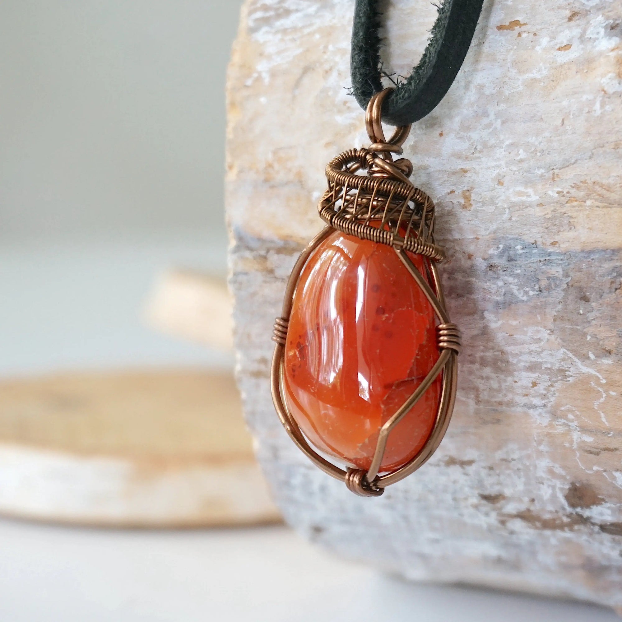 Left angle close-up of men's carnelian necklace – highlighting unique wire-wrapped artistry, orange carnelian, black leather cord.