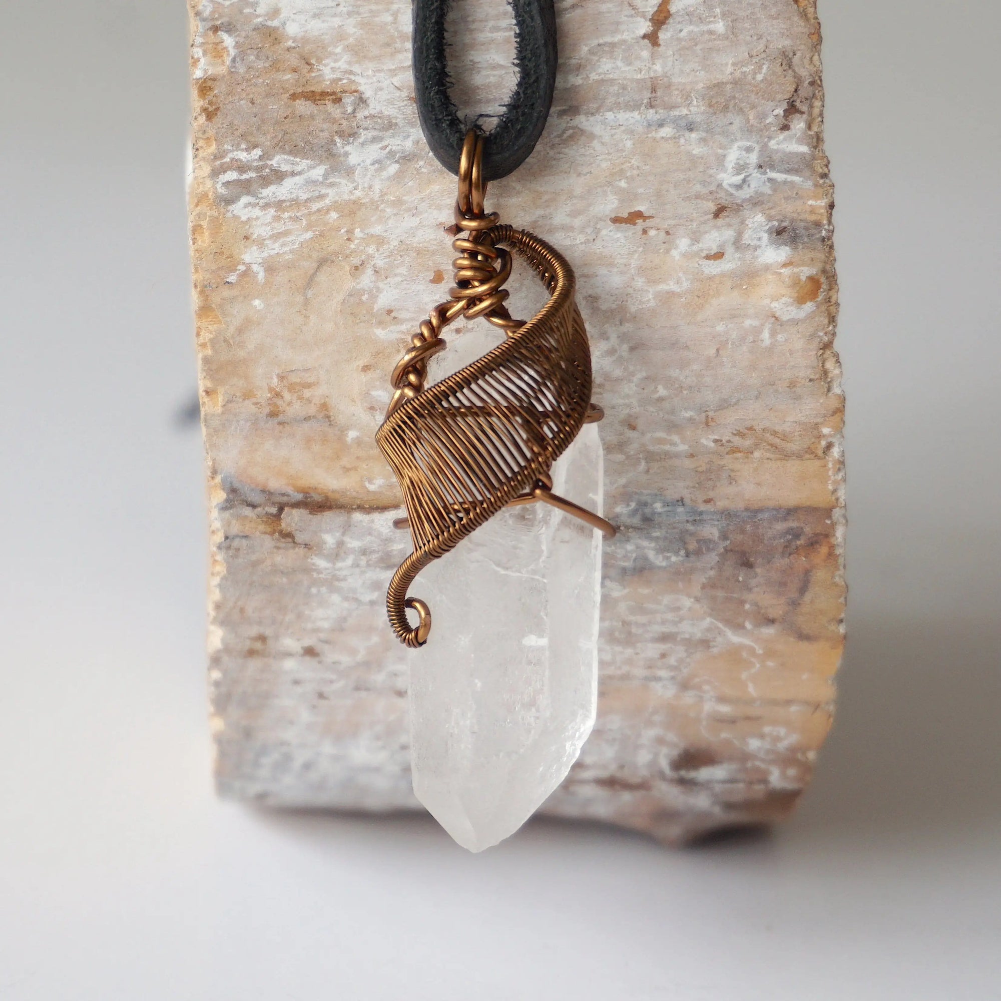 Handcrafted clear quartz point necklace for men, front view – artisan antique bronze copper wire wrapping, April birthstone, black leather cord.