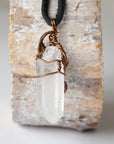 Back view of handcrafted clear quartz point necklace for men – natural stone and wire wrapping, April birthstone, black leather cord.