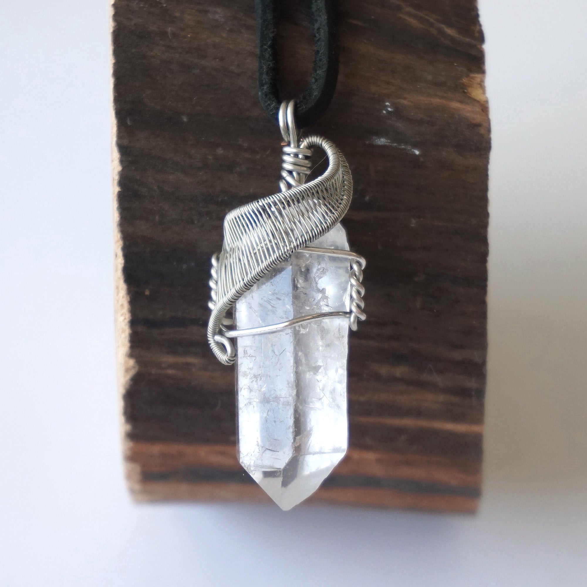 Handcrafted clear quartz point necklace for men, front view – artisan white gold copper wire wrapping, April birthstone, black leather cord.