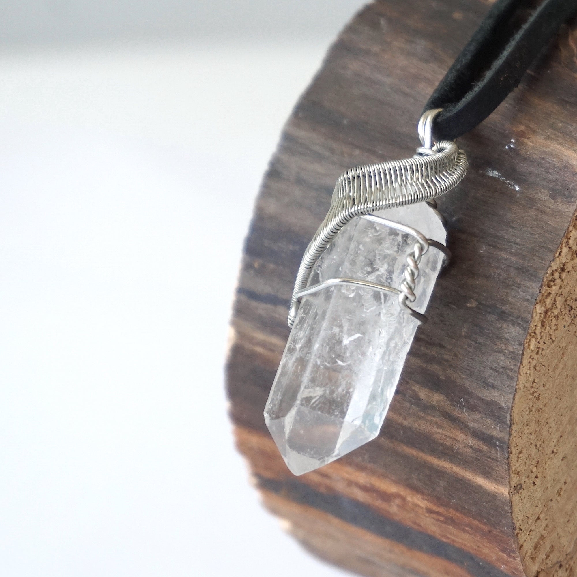 Left angle close-up of clear quartz point necklace for men – highlighting unique wire-wrapped artistry, clear quartz, black leather cord.