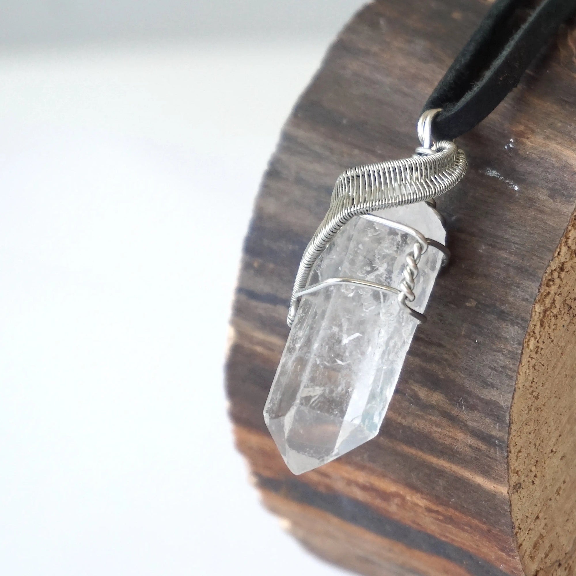 Left angle close-up of clear quartz point necklace for men – highlighting unique wire-wrapped artistry, clear quartz, black leather cord.