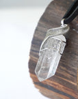 Left angle close-up of clear quartz point necklace for men – highlighting unique wire-wrapped artistry, clear quartz, black leather cord.