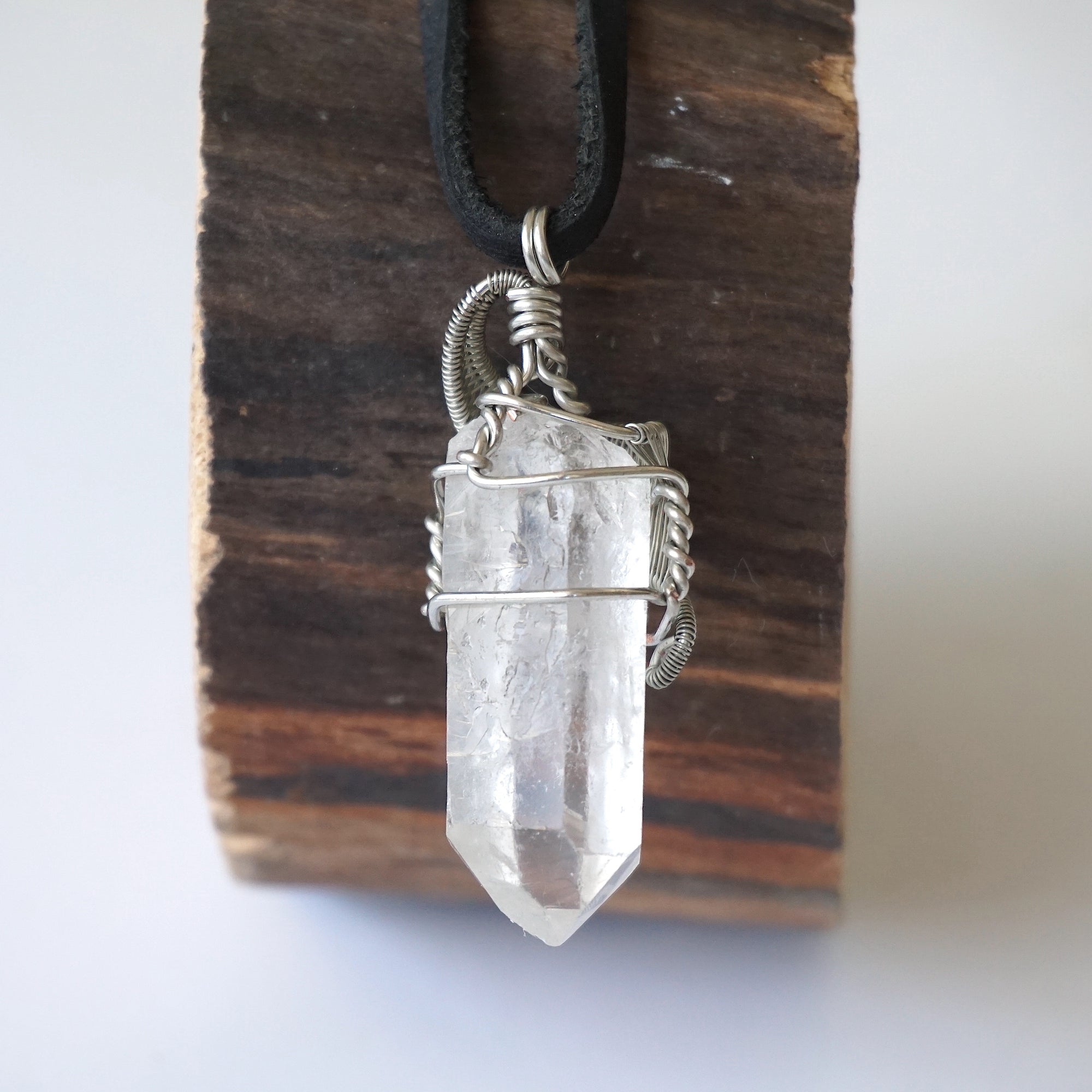 Back view of handcrafted clear quartz point necklace for men – natural stone and wire wrapping, April birthstone, black leather cord.