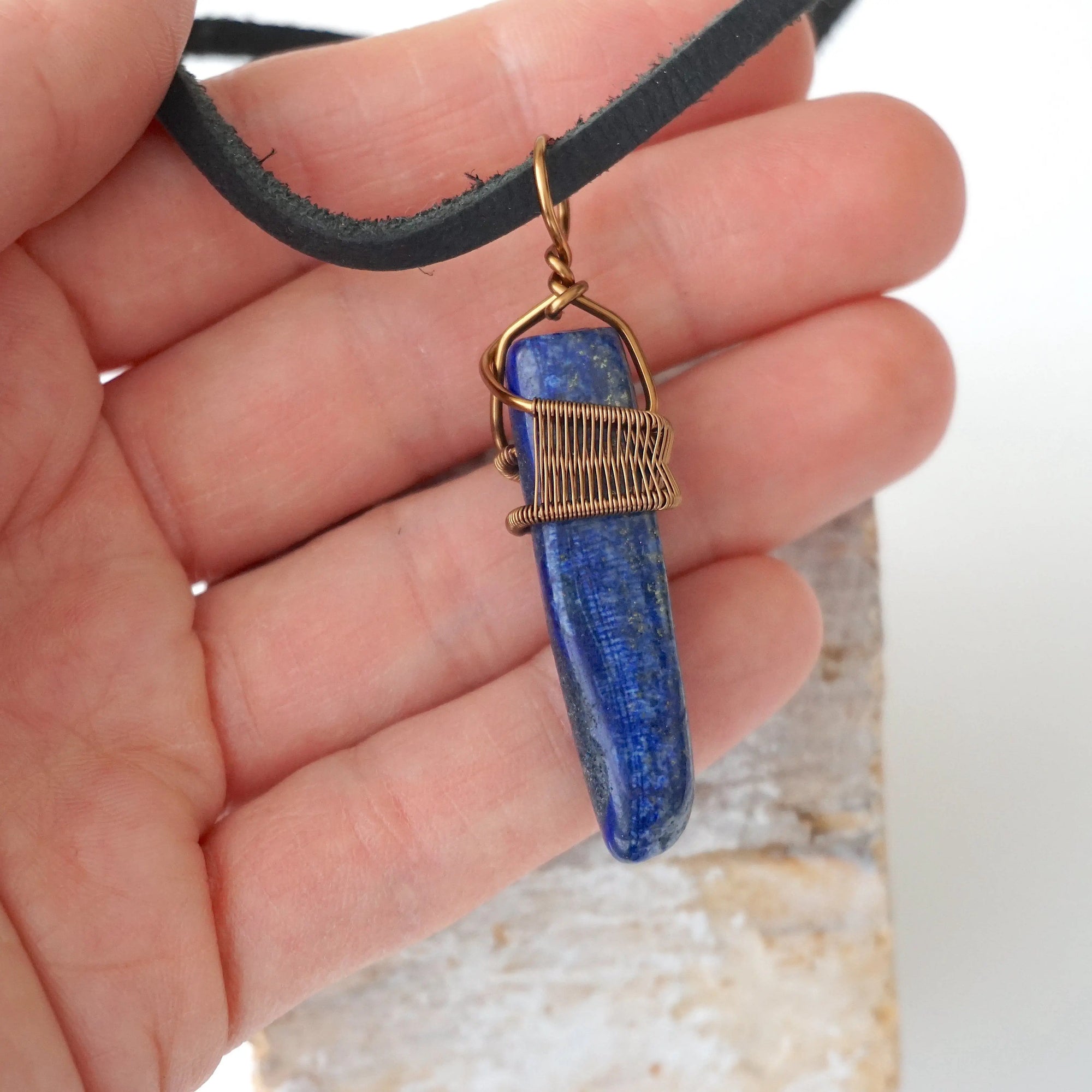 Lapis lazuli point necklace for men in hand for size reference – genuine blue stone, antique bronze copper wire, masculine design.