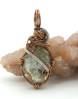 Pendant with green stone and bronze wire wrapping on a white background