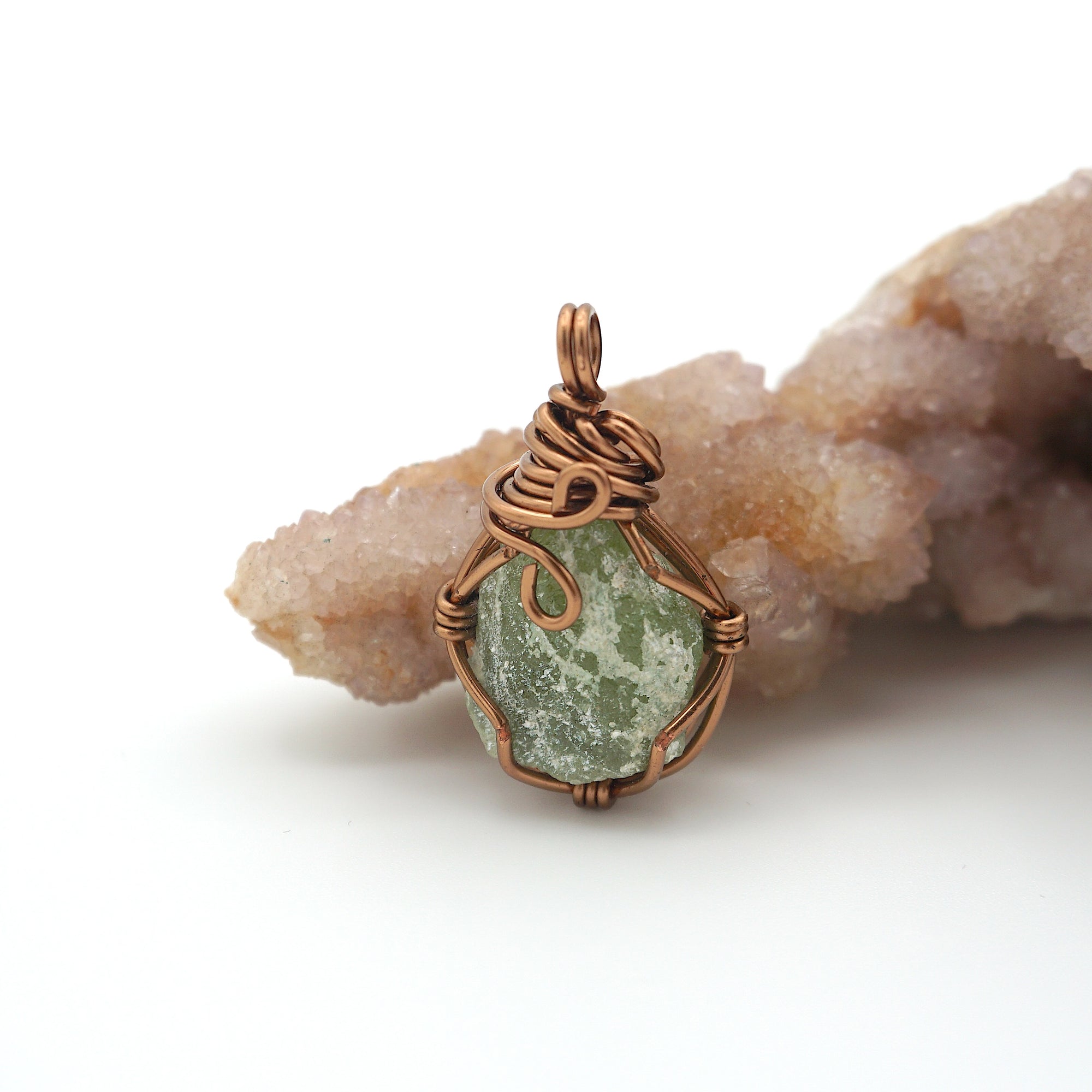 Copper pendant with green stone on a rock formation