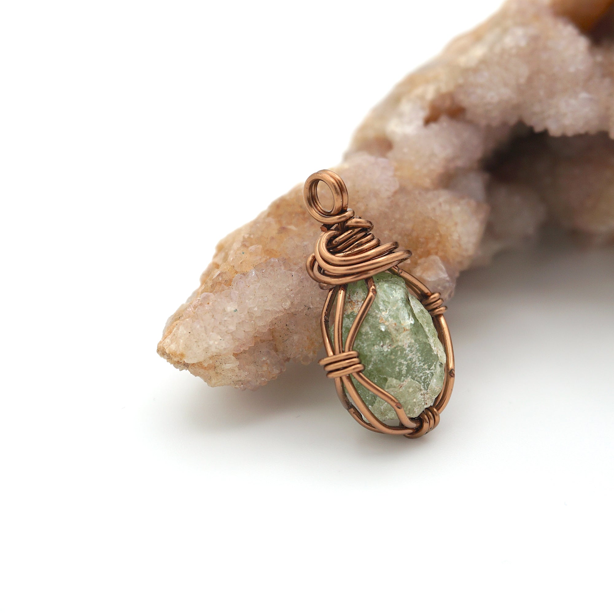 Copper-wrapped green stone pendant on a white background