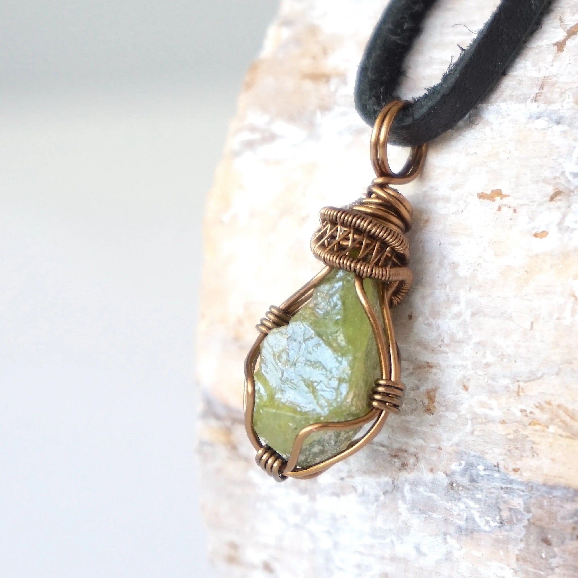 Left angle close-up of men's peridot necklace – highlighting unique wire-wrapped artistry, green peridot, black leather cord.