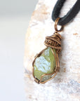 Left angle close-up of men's peridot necklace – highlighting unique wire-wrapped artistry, green peridot, black leather cord.