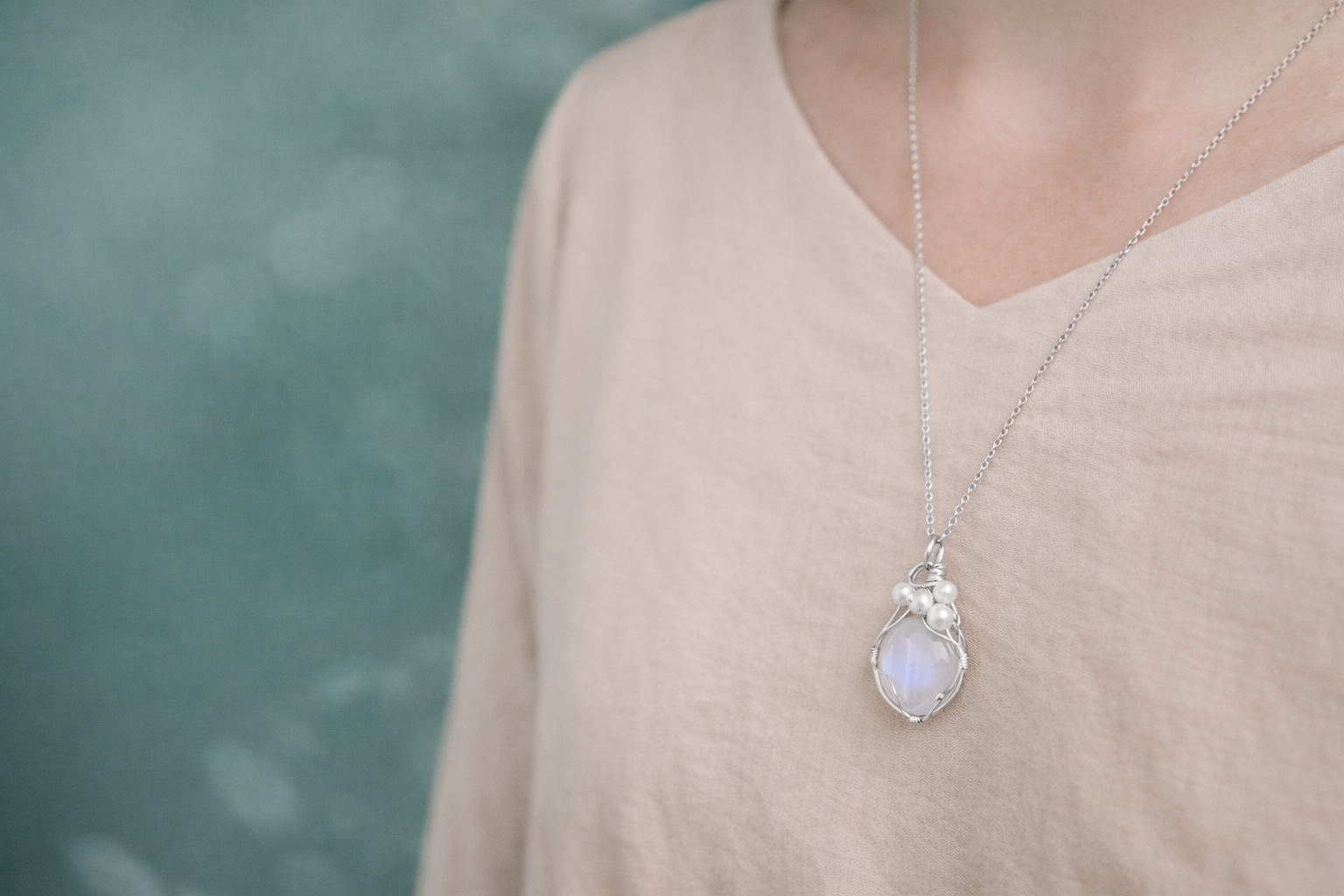 Person wearing a necklace with a heart-shaped pendant against a blurred background