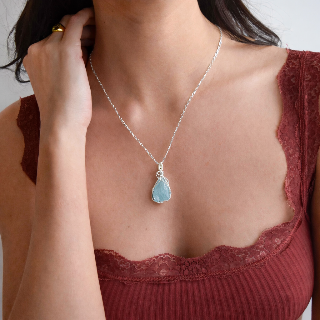 Necklace with a blue gemstone pendant worn by a person in a red top.