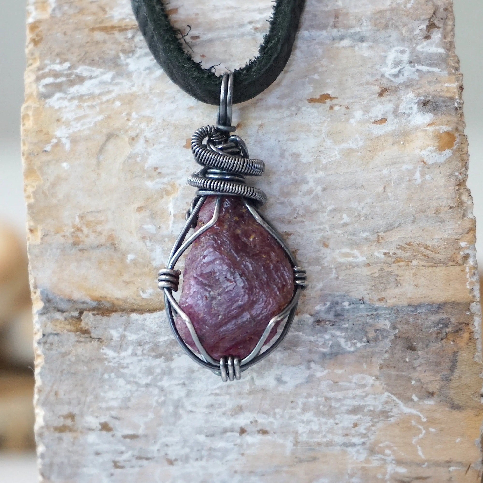Handcrafted raw ruby necklace for men, front view – artisan antiqued sterling silver wire wrapping, July birthstone, black leather cord.