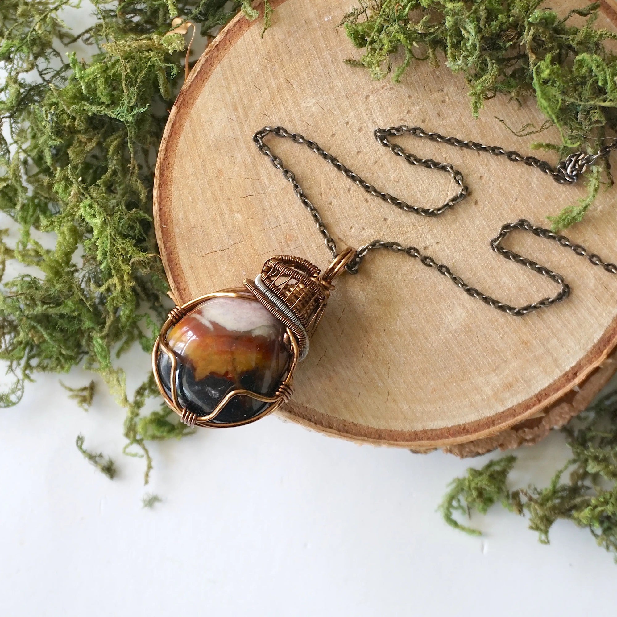 Handcrafted raw sardonyx necklace laying flat – artisan bronze and dark silver copper wire wrapping, August birthstone jewelry for all genders, Designs by Nature Gems.