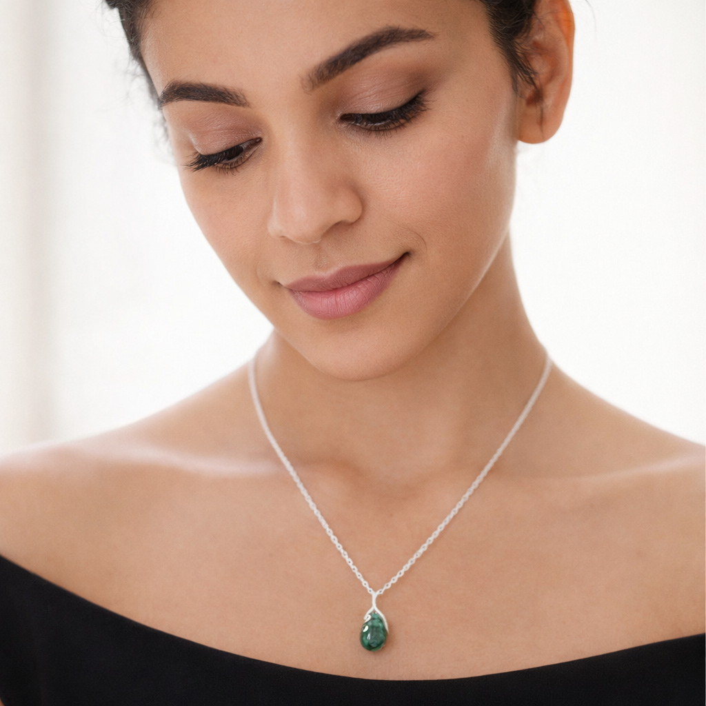 Woman wearing a silver necklace with a green pendant on a white background