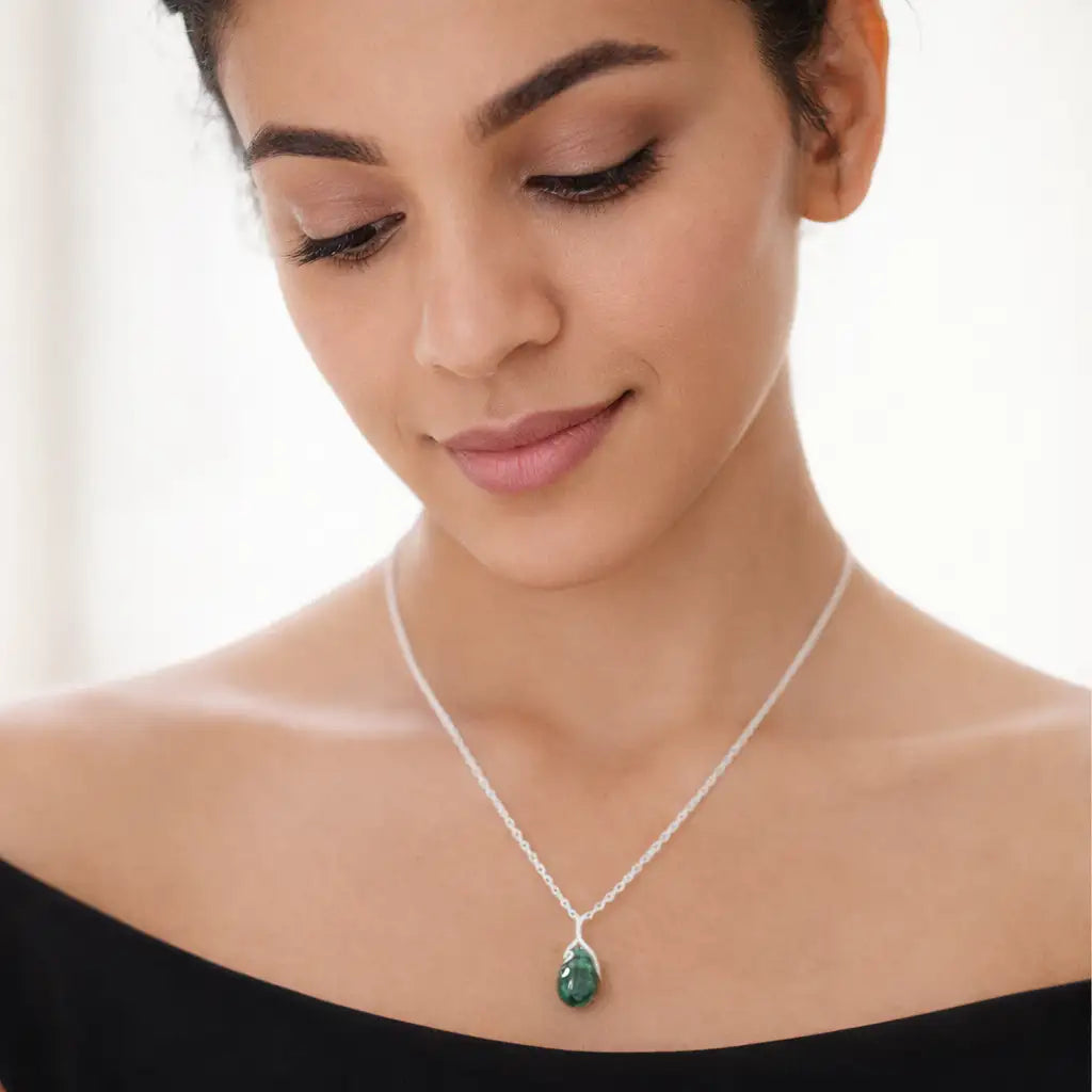 Woman wearing a silver necklace with a green pendant on a white background