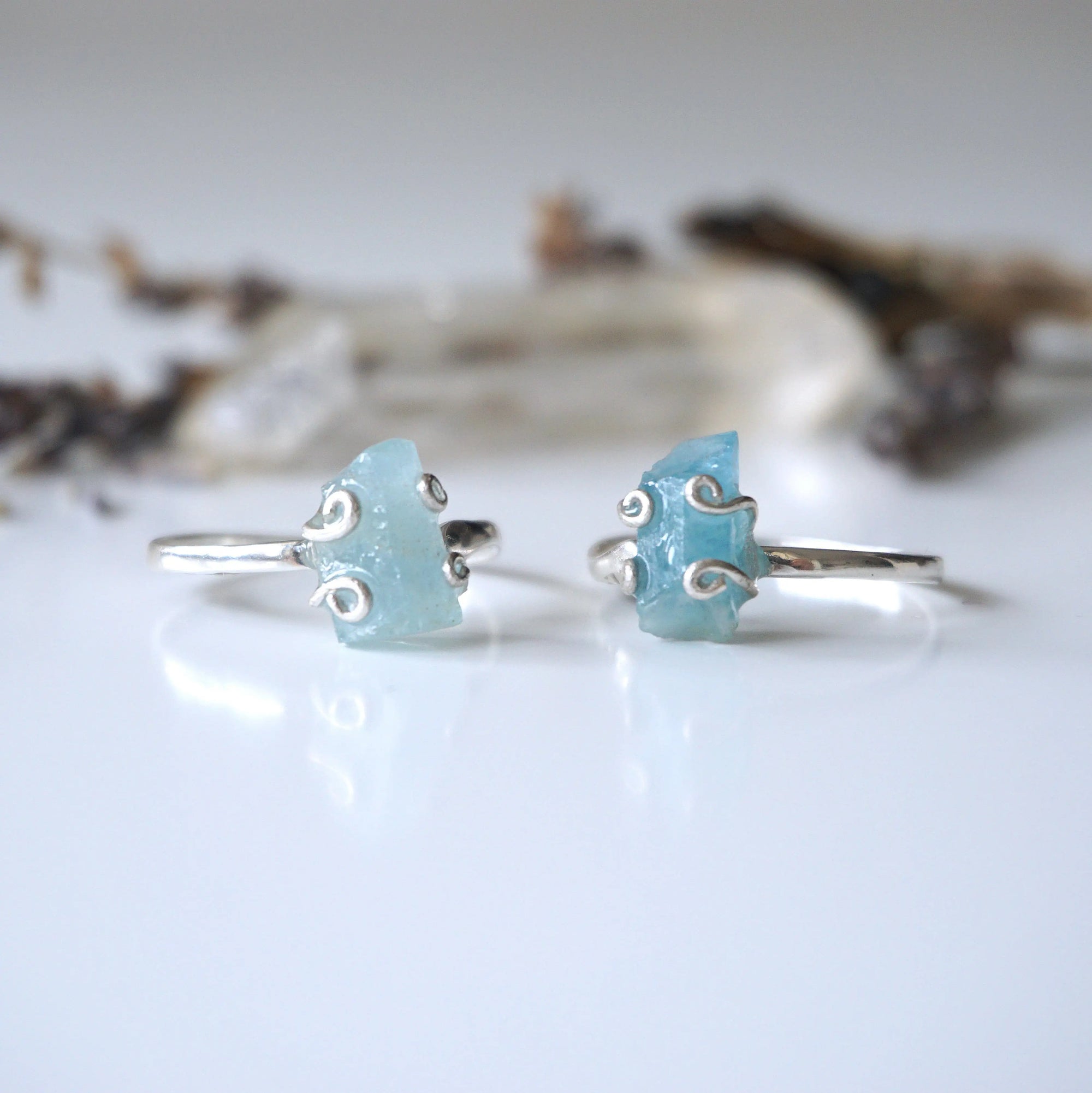 Two adjustable aquamarine rings side by side, showing natural variation in aquamarine's size, shape, and color, 925 sterling silver